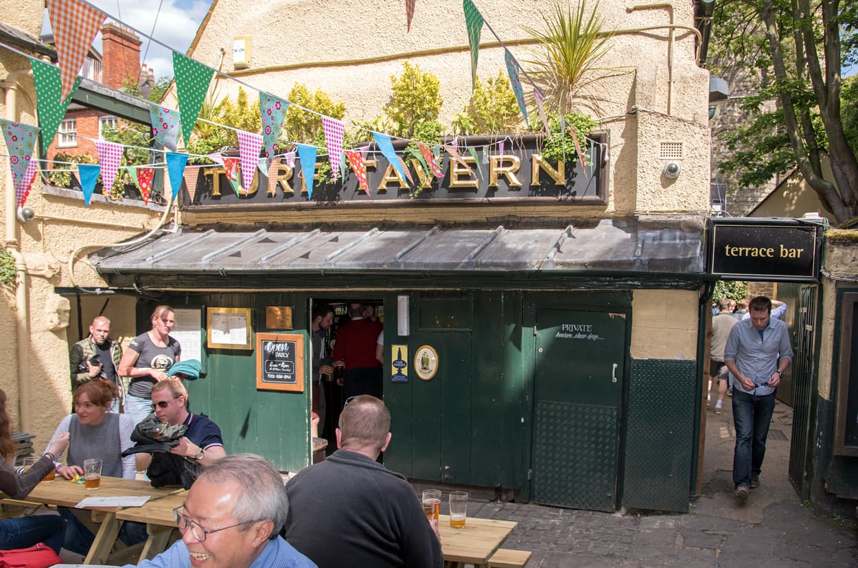 Patrons enjoying pints in the historic courtyard of the Turf Tavern in Oxford